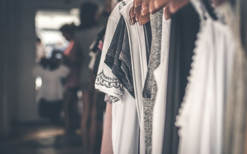 Neutral clothing on wooden hangers in a boutique wardrobe